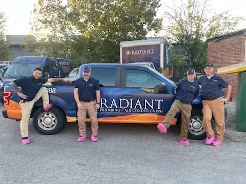 Four Radiant technicians lined up in front of a Radiant truck showing off pink shoe covers