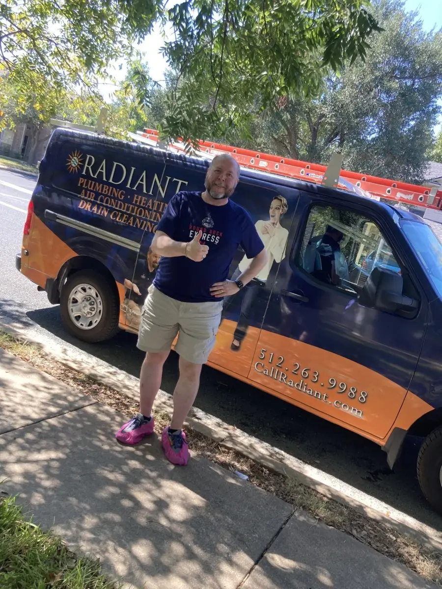 Radiant technician giving a thumbs up beside a Radiant van while wearing pink shoe covers