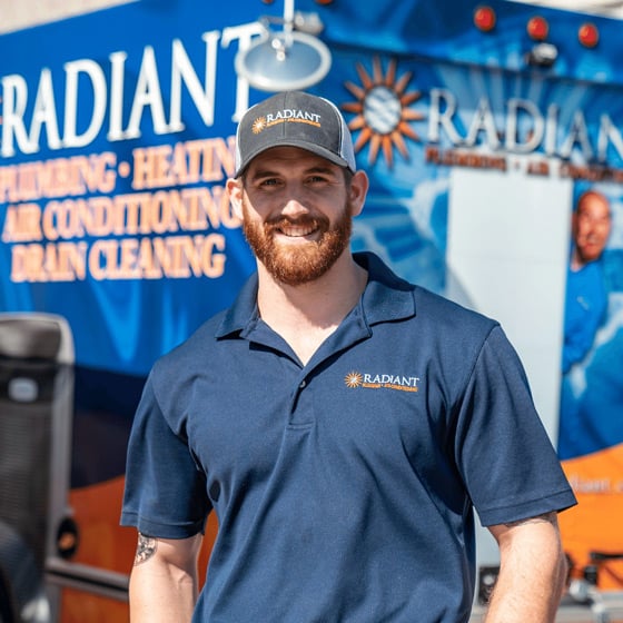 Radiant technician smiling at the camera in front of a work truck