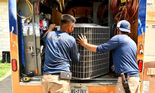 Two Radiant HVAC technician taking an AC off of a truck