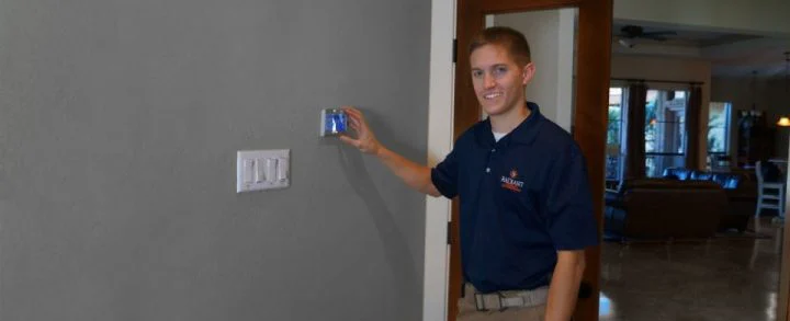 Radiant technician smiling at camera with hands on smart thermostat