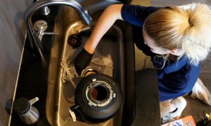 A Radiant technician fixing a leaking garbage disposal
