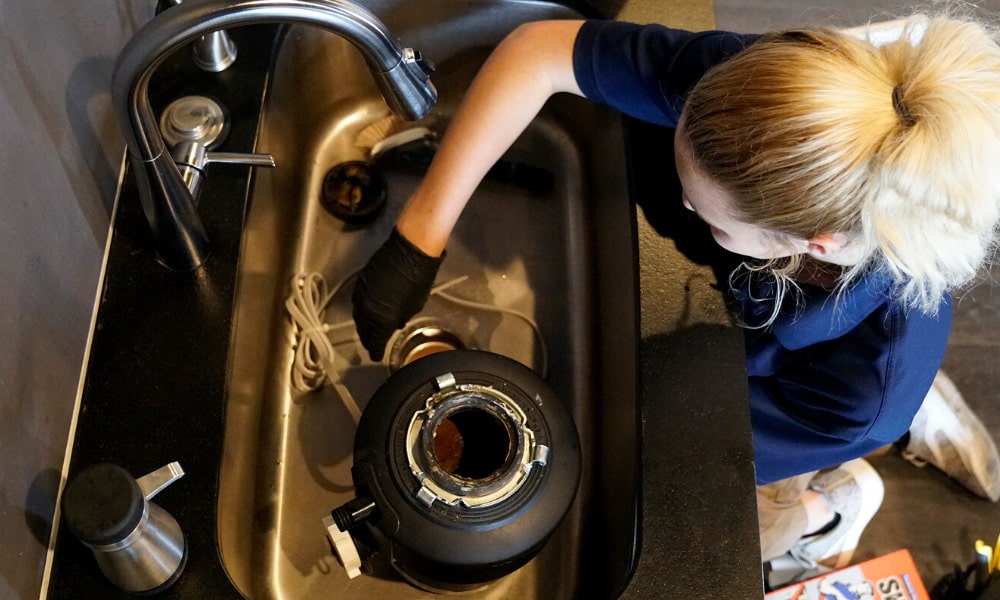 A Radiant technician fixing a leaking garbage disposal