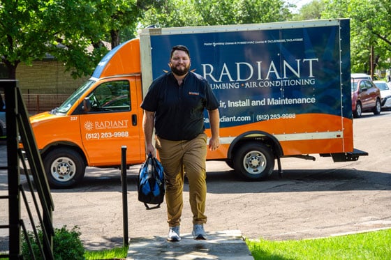 A Radiant Tech walking to a house with his tool bag in hand.