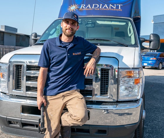 Radiant Plumbing and Air technician leaning on the hood of a work truck