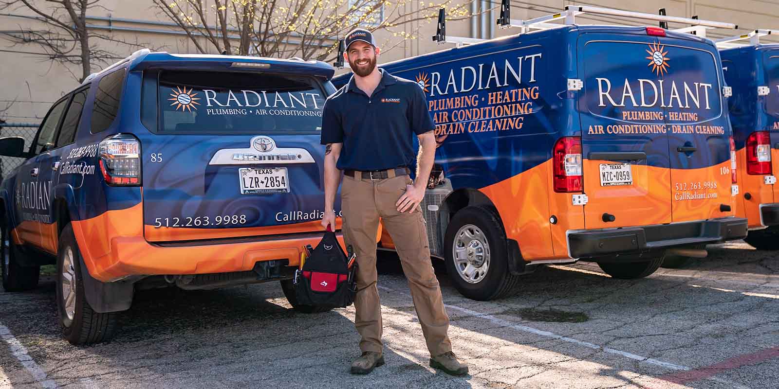 Radiant Plumbing and Air technician standing in front of parked work trucks
