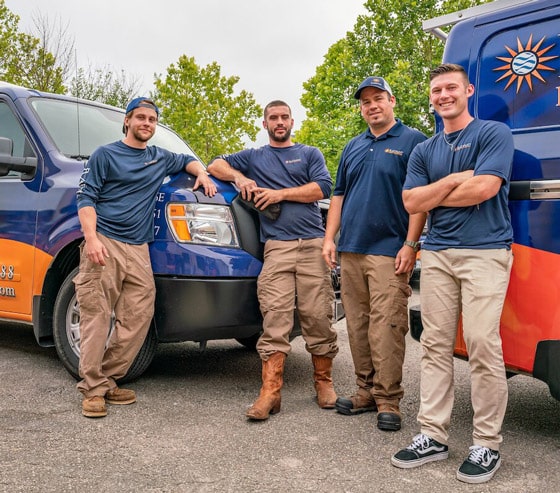 The Radiant Plumbing team standing and leaning on work trucks