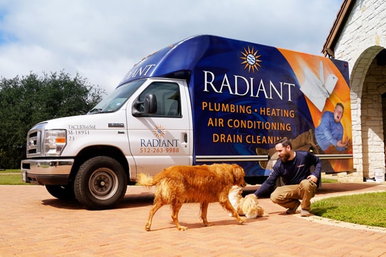 Radiant technician and dogs playing in front of a work truck