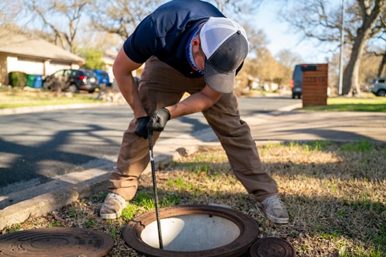 A Radiant technician inspecting a drain from the manhole in a yard