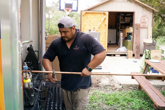 Radiant technician cuts copper piping for home gas line repair