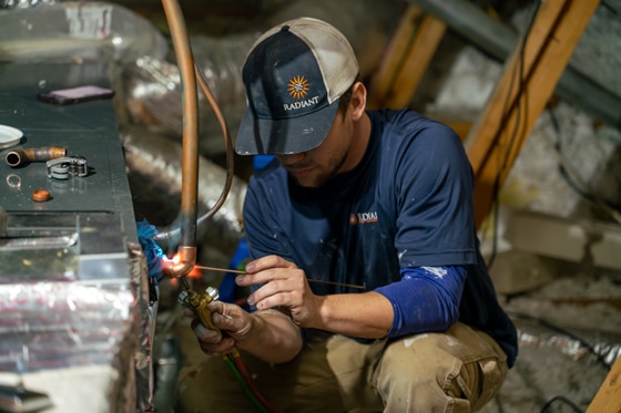 Radiant technician repairing an HVAC unit in an attic