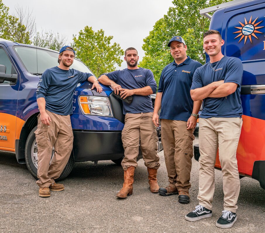 The Radiant Plumbing team standing and leaning on work trucks.