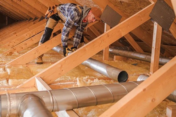 Technician installing ducting work in an attic
