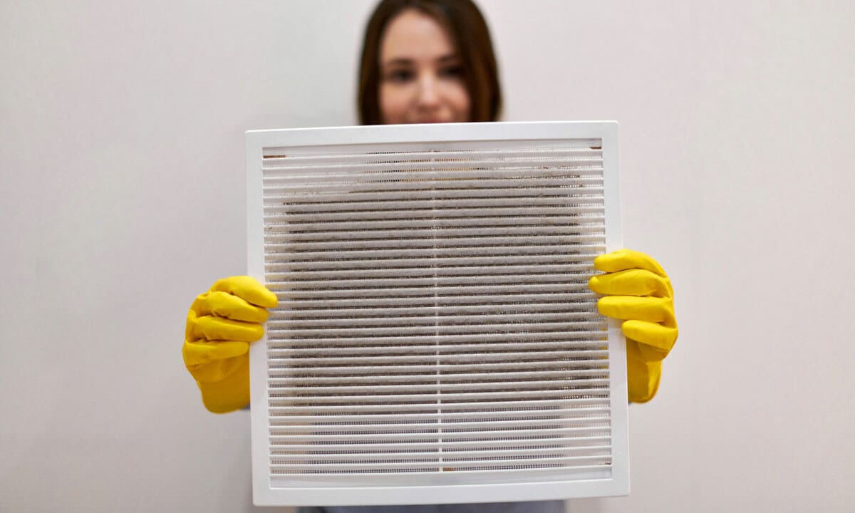 A woman holding up a dirty air filter