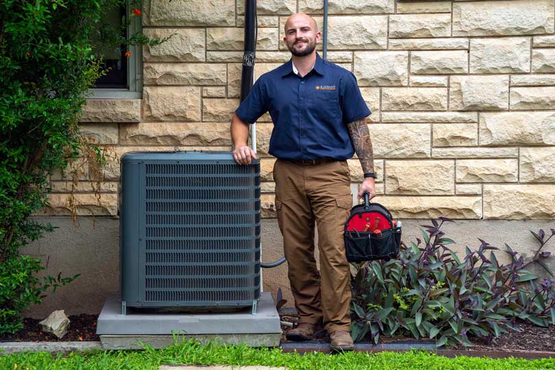 The Radiant HVAC technician standing next to an air conditioner