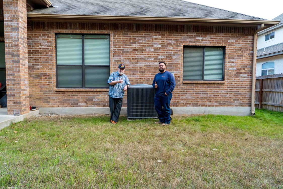Radiant HVAC technician and customer standing next to recently installed AC unit