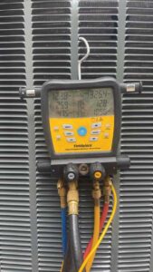 HVAC technician testing refrigerant levels on new AC system using digital gauges