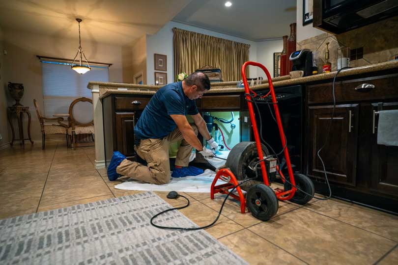 A Radiant drain technician clearing a kitchen drain clog