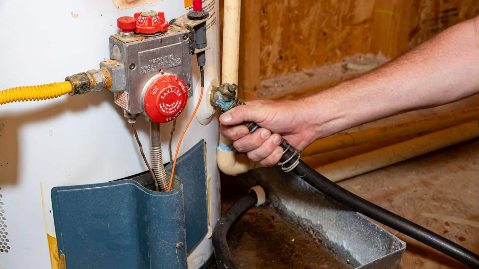 A person attaching the hose to drain a water heater