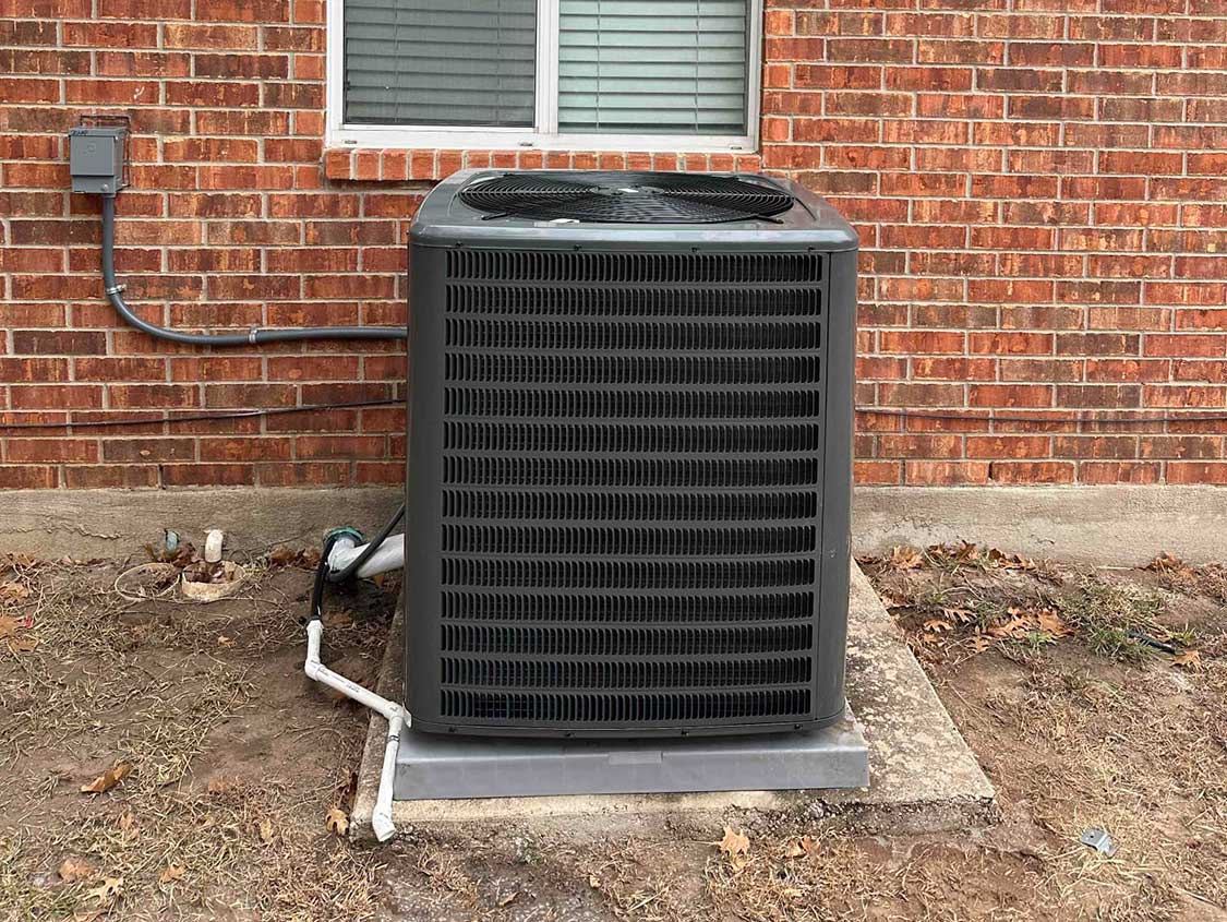 A new Goodman HVAC condenser unit installed outside a home on a concrete slab.