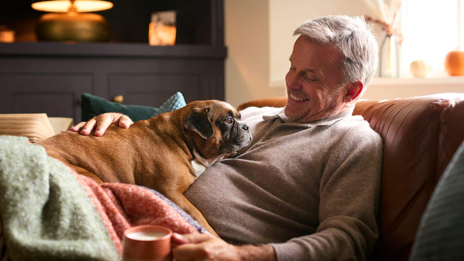 A man and his dog sitting on a couch in a warm home.