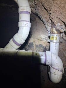 New schedule-rated PVC sewer pipe installed beneath the slab inside the excavation tunnel.