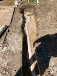 A plumbing trench with newly installed and partially filled hole