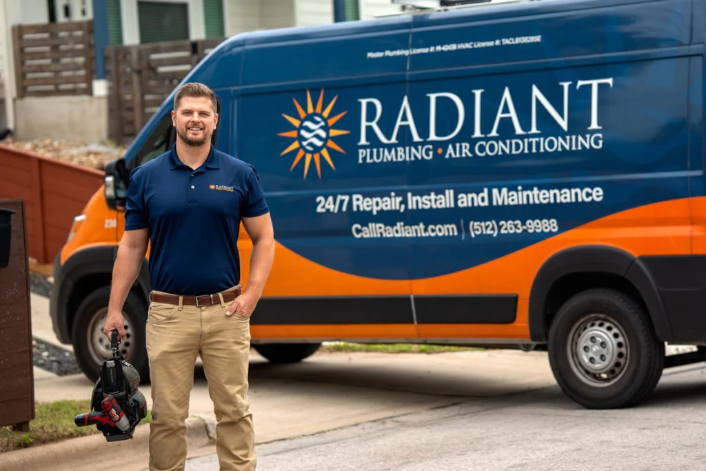 Radiant installer with a tool bag beside a service van at an Austin home before a furnace replacement