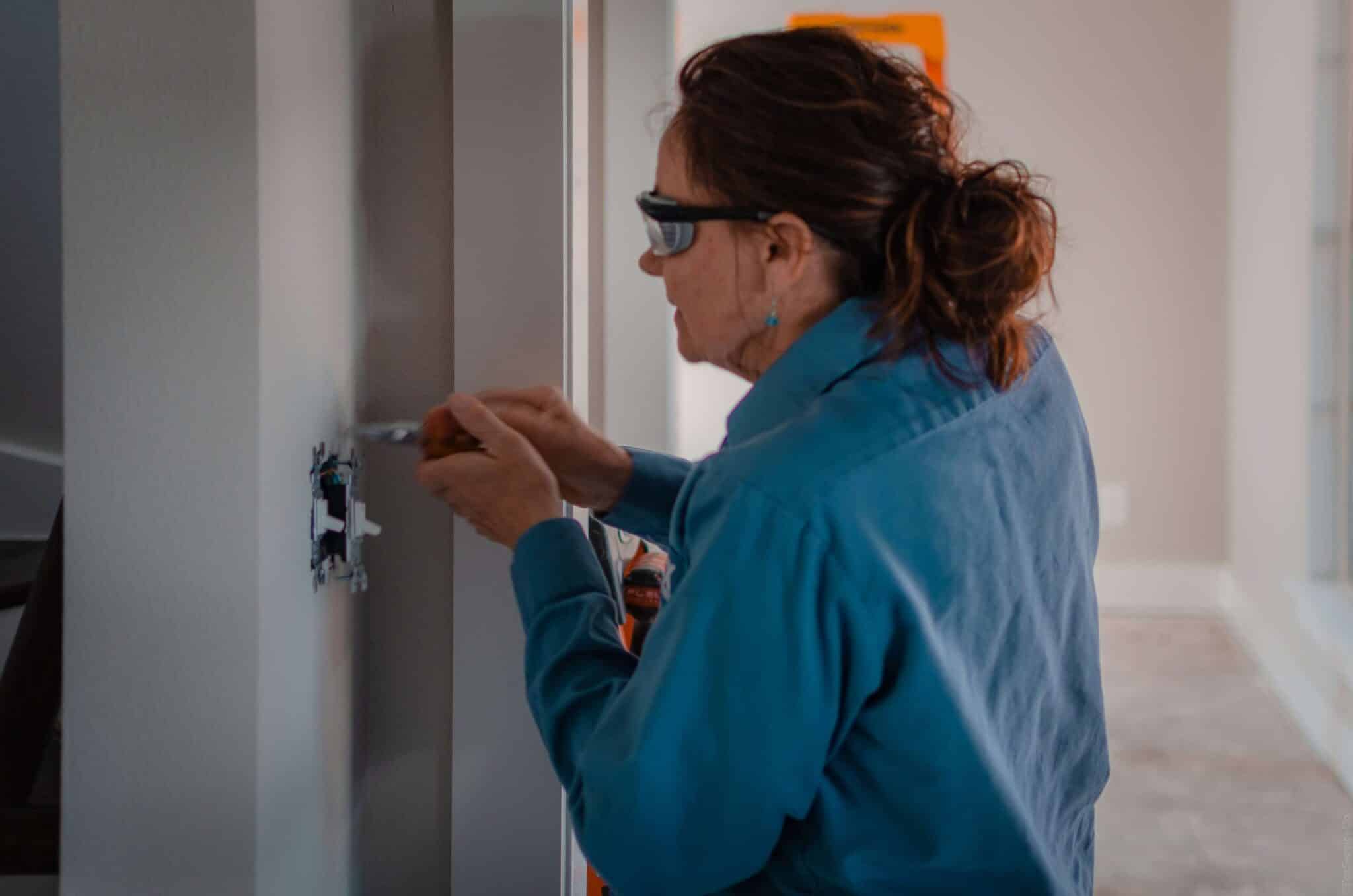 Photo of Deborah an electrician working on an switch on a wall
