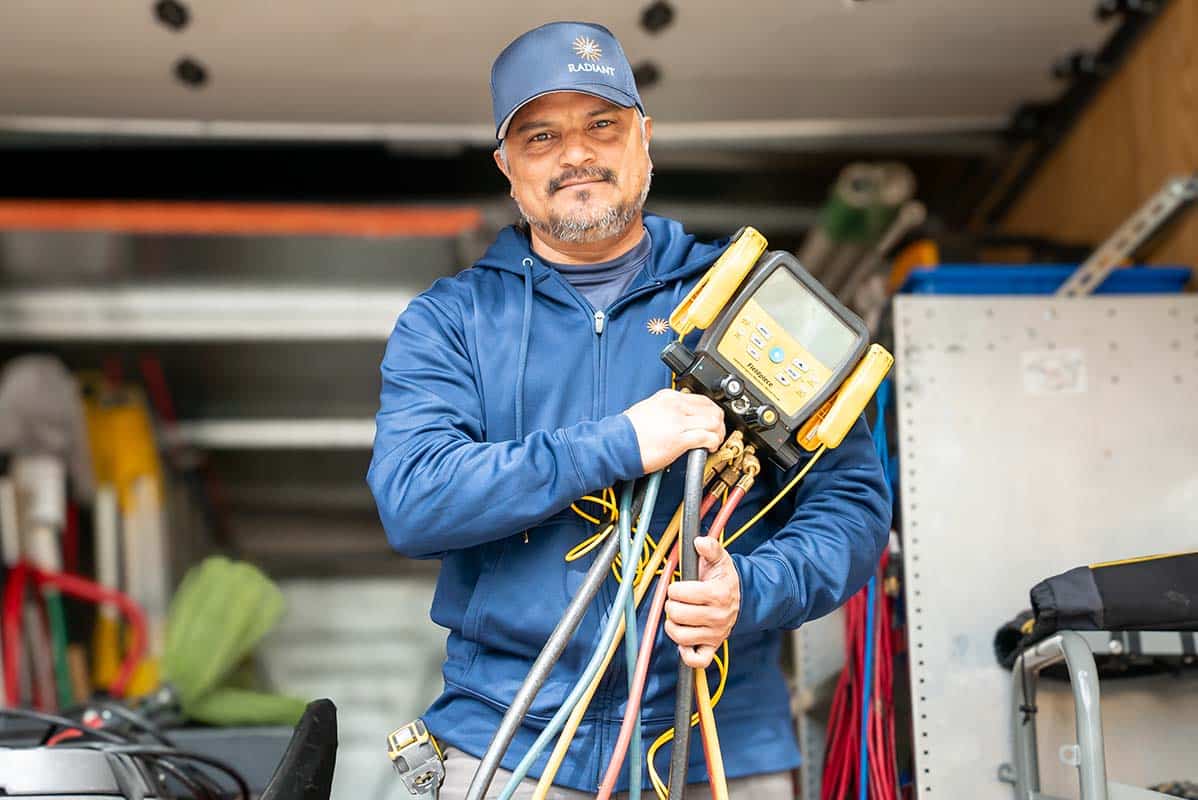 A Radiant Technician standing in the back of a truck holding Aeroseal testing equipment