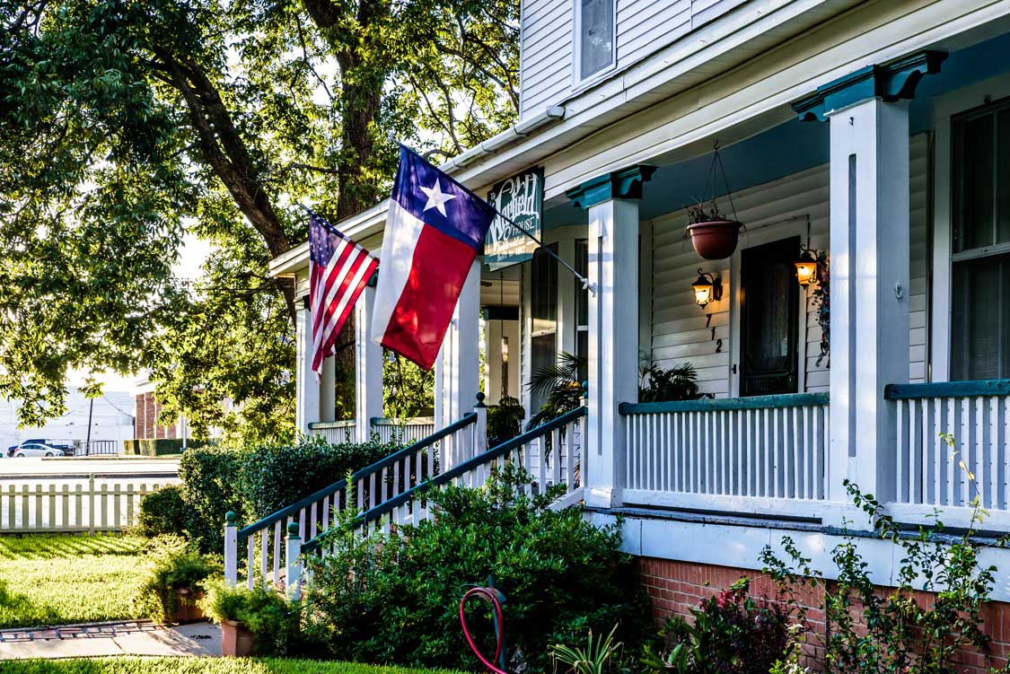 A home with a US Flag and Texas flag flying out front