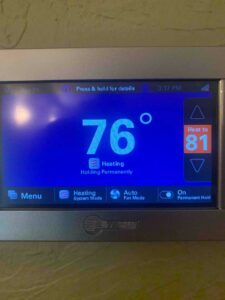 Trane touchscreen thermostat displaying indoor temperature during system testing